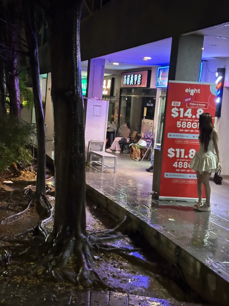 雨上がりの夜のゲイラン。ネオンが反射する歩道と通りの人々